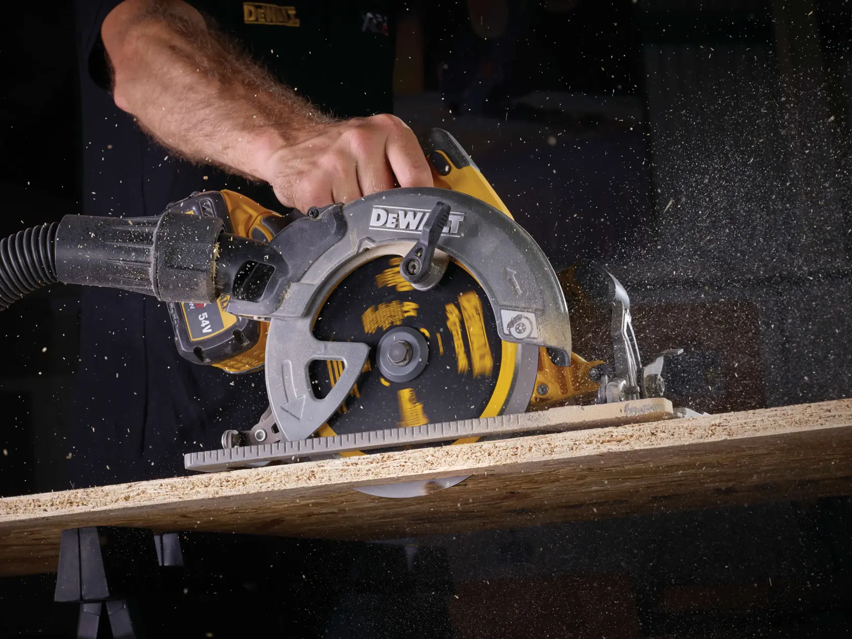 Sega circolare DEWALT taglia il legno, segatura dispersa, mano dell’operatore visibile.
