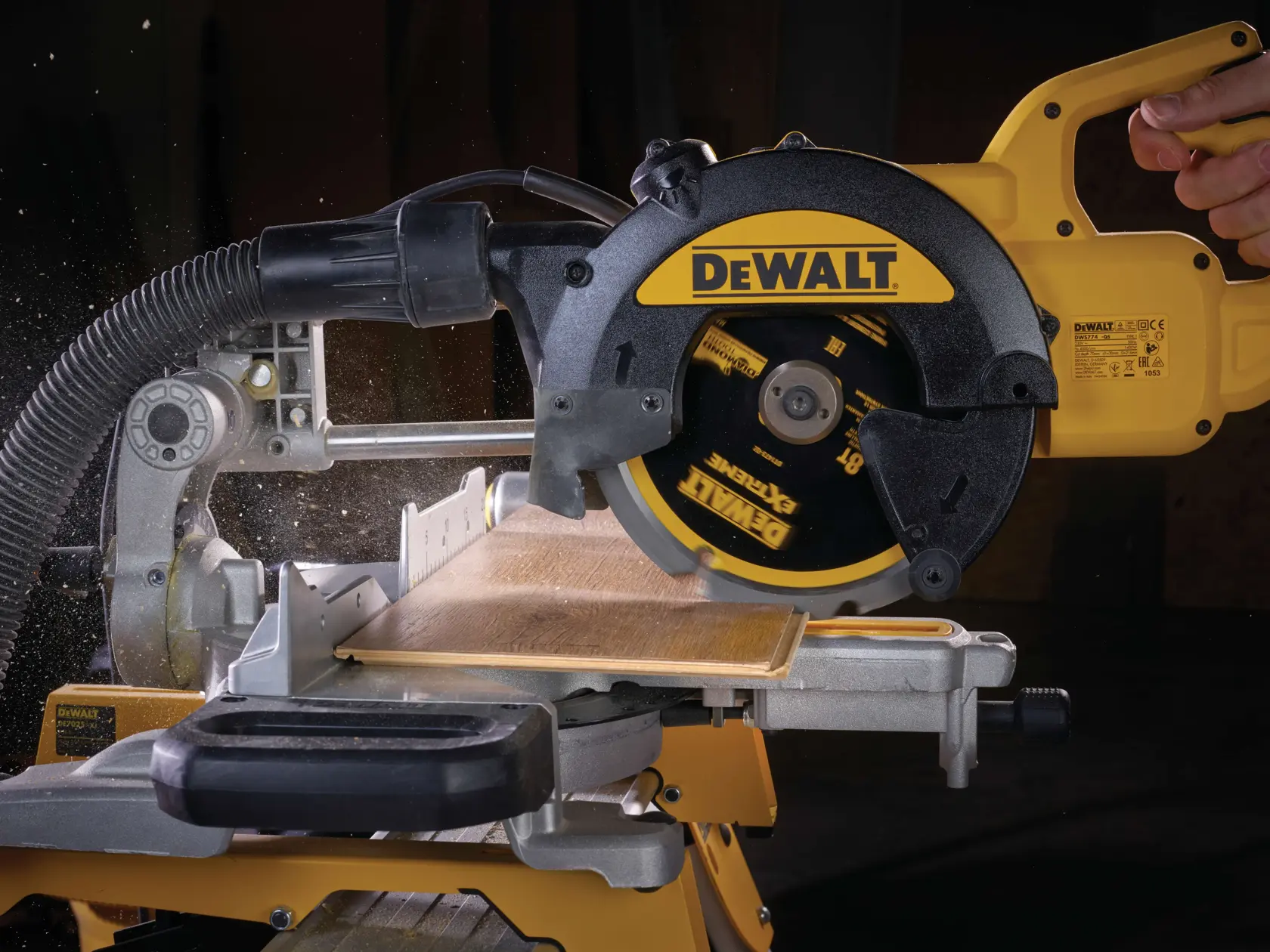 Sega circolare DEWALT taglia legno, primo piano con tubo d’aspirazione, lama in funzione.