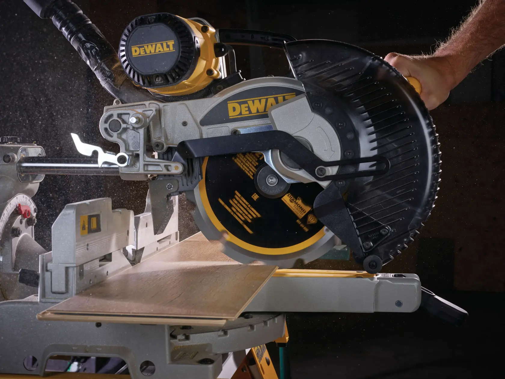 Troncatrice DEWALT taglia una tavola di legno, vista ravvicinata, particelle di polvere visibili.