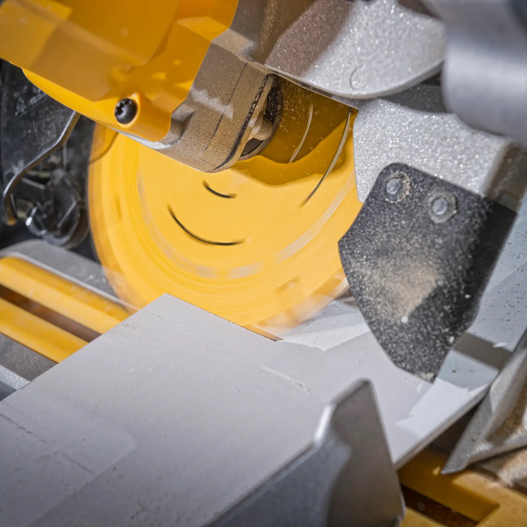Close-up of a DEWALT circular saw cutting a piece of material. Saw blade is spinning and generating dust.