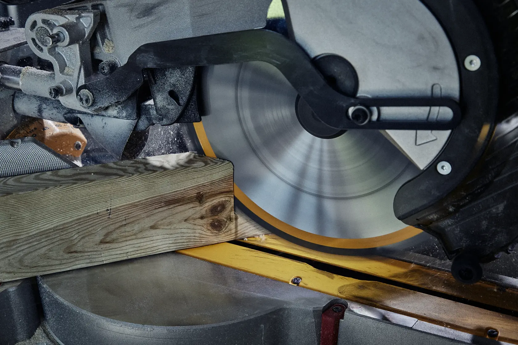 Primo piano di una sega circolare che taglia una tavola di legno.