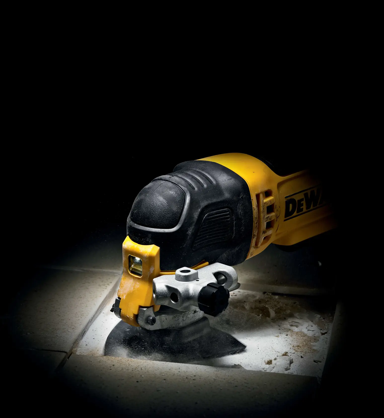 DEWALT multi-tool cutting through tile, creating dust and debris on a tiled surface.