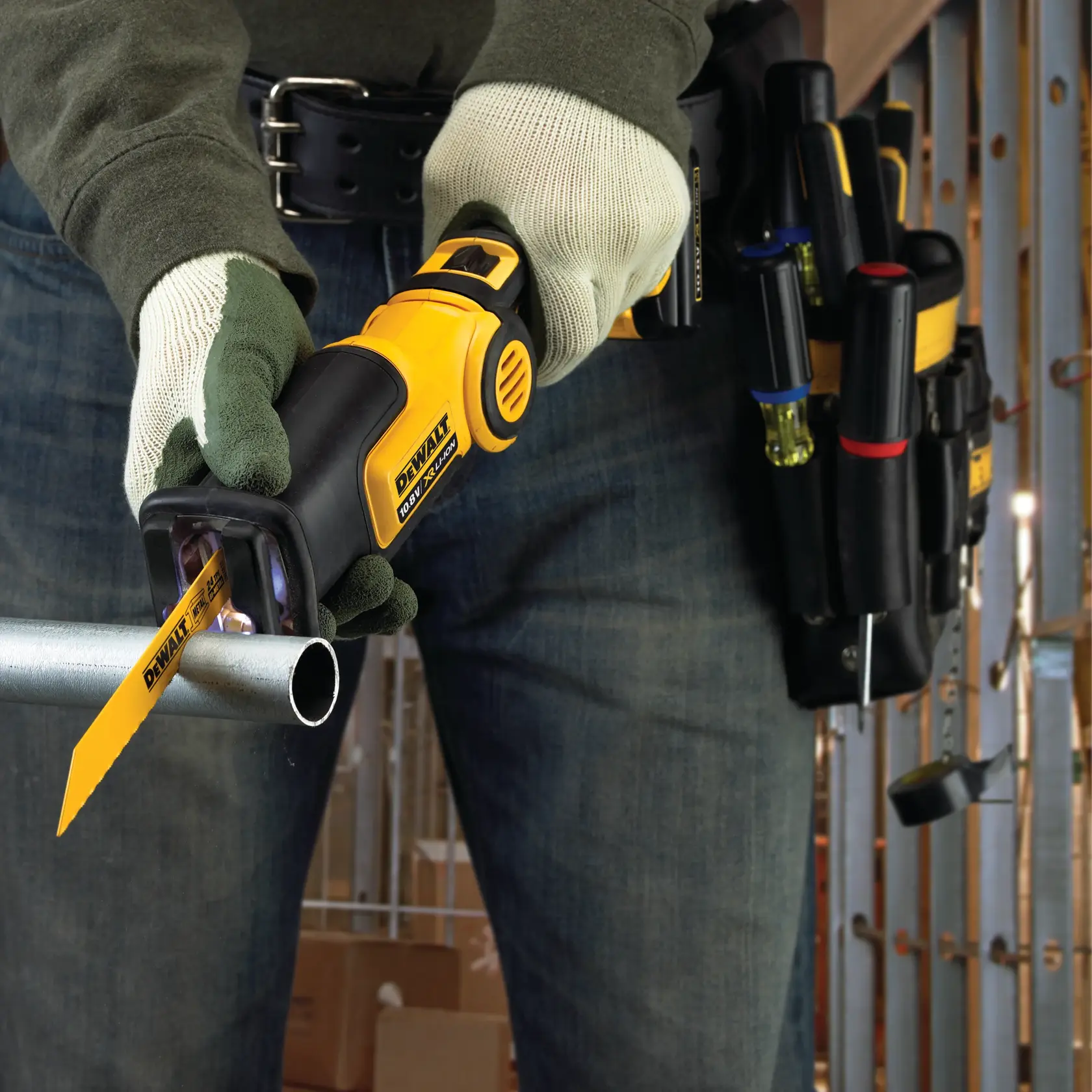 Persona usa seghetto DEWALT per tagliare tubo metallico; visibile cintura attrezzi e guanti.
