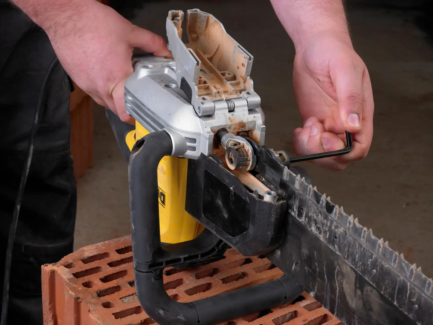 Person uses a hex key to adjust or maintain a DEWALT saw on a brick surface.