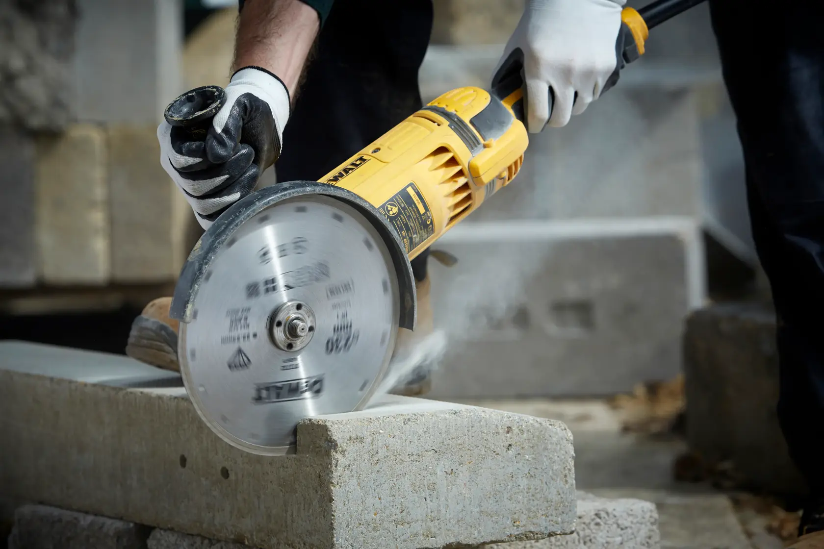 Herramienta DEWALT cortando bloque de concreto. El trabajador usa guantes de seguridad.