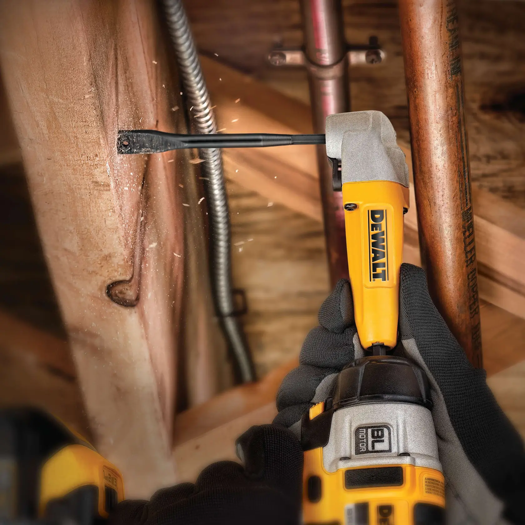 Trapano DEWALT in uso, trapana il legno in uno spazio ristretto, con guanti, vicino tubi e cavi.
