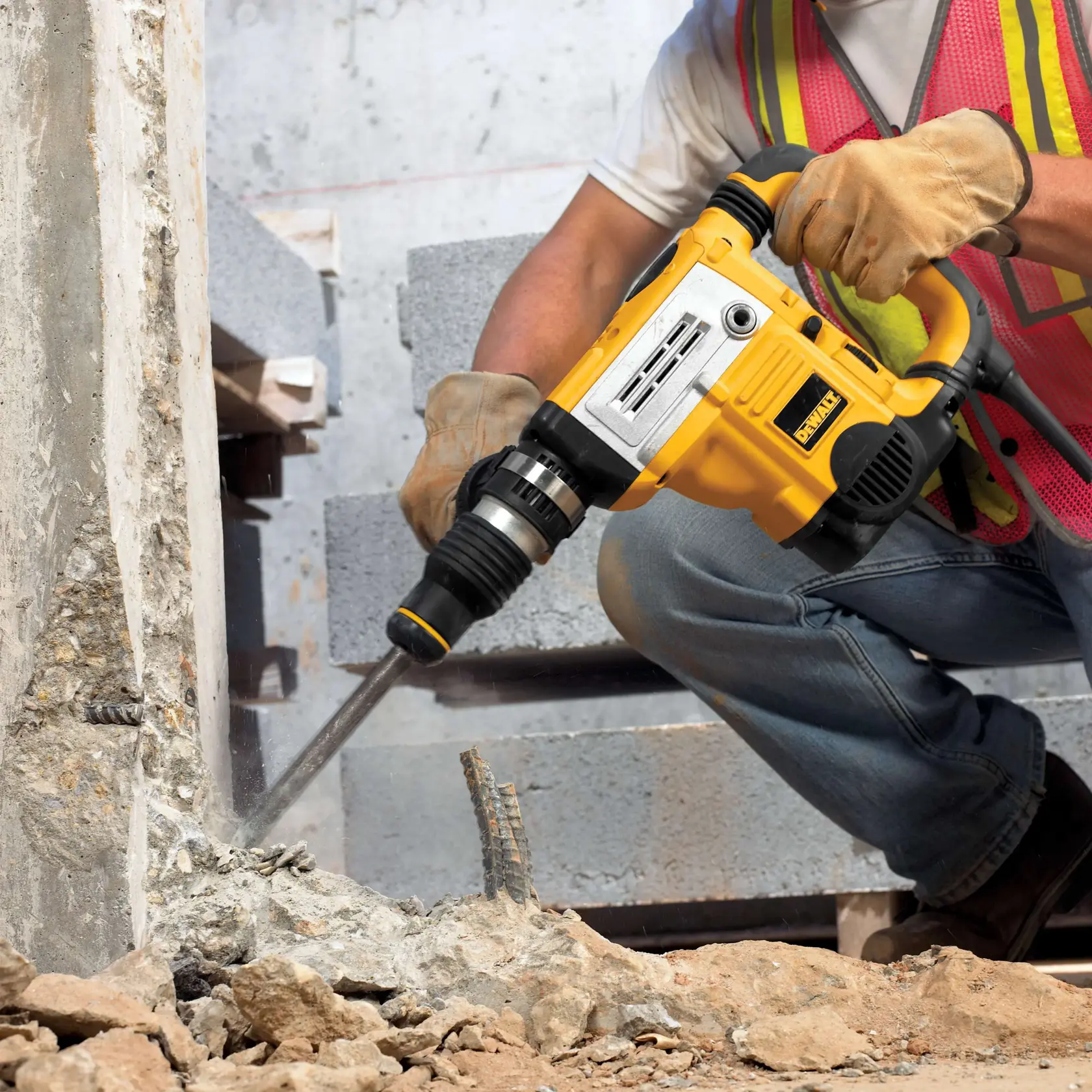 DEWALT DT6824 Bohrhammer zerkleinert Beton auf Baustelle. Arbeiter trägt Handschuhe und Sicherheitsweste.