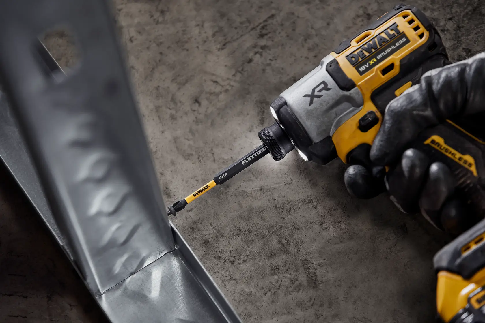 Un avvitatore a impulsi DEWALT con punta FlexTorq avvita su una superficie metallica.