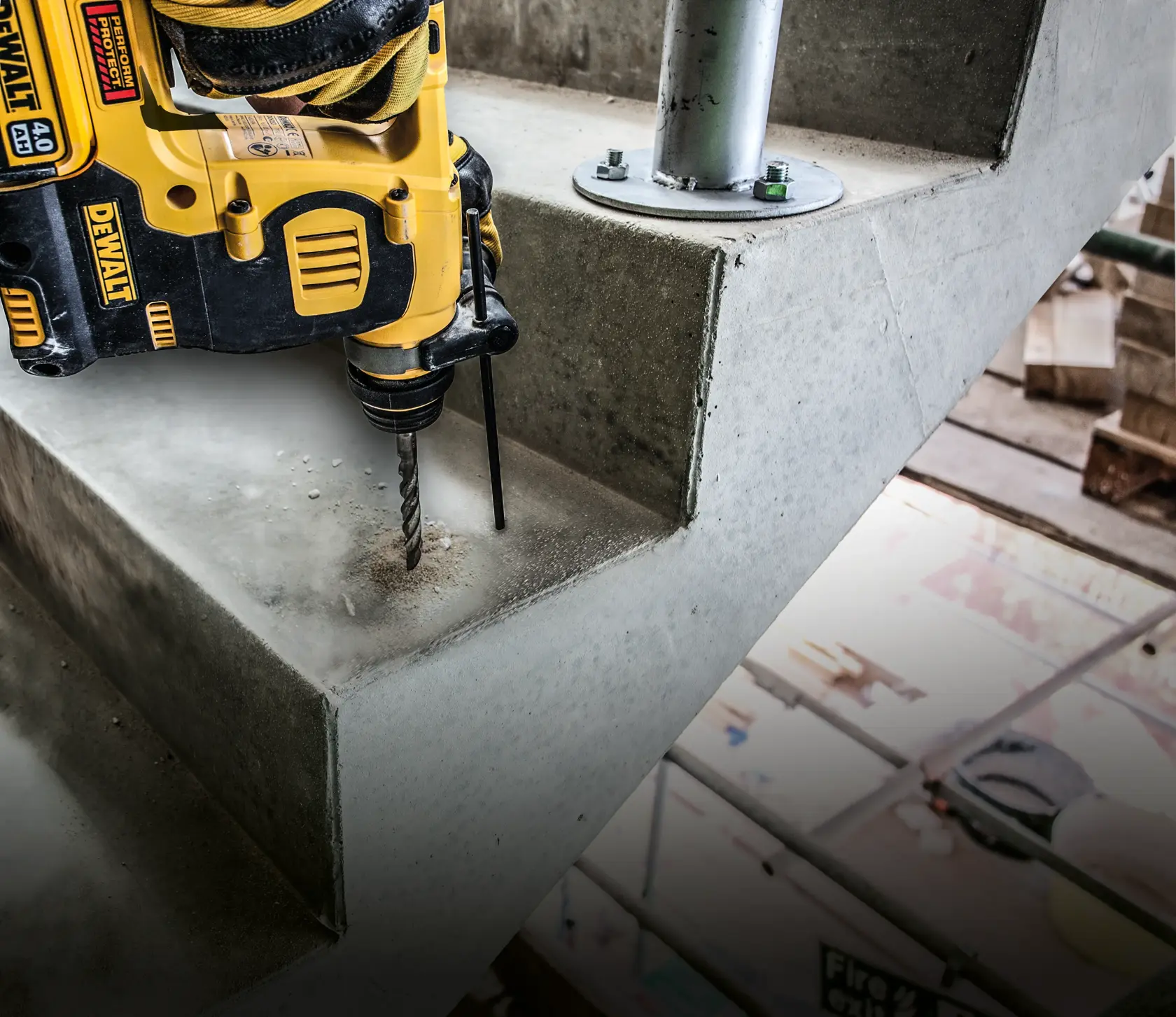 Close-up of a metal drill bit cutting into concrete, dust and particles flying around.