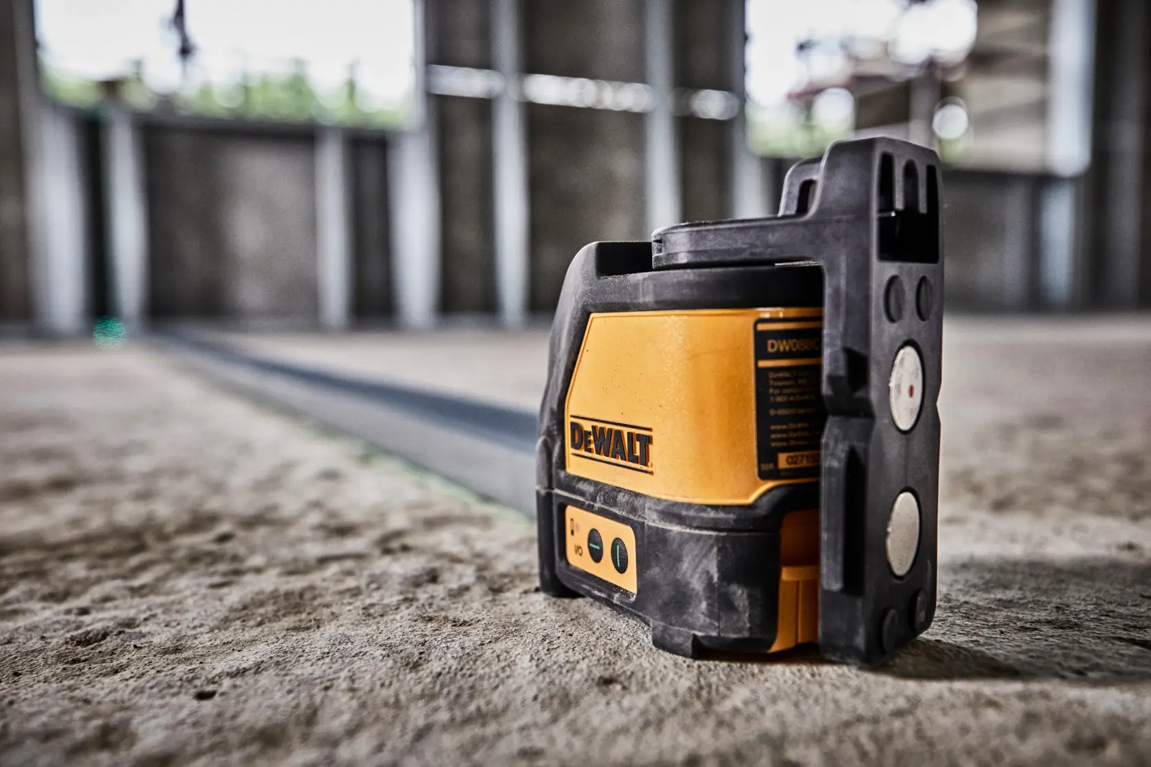 DEWALT green laser level DW088CG on a construction site floor for precise alignment work.