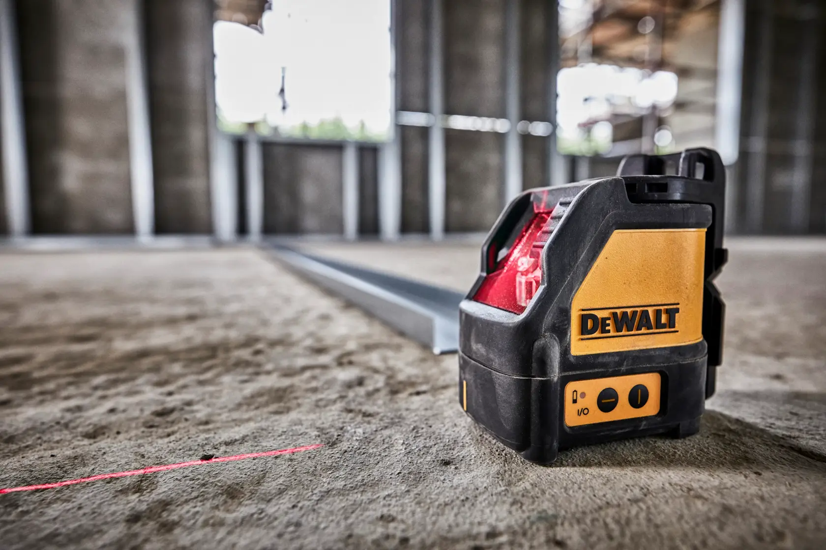 DEWALT laser level emits a red line on a construction site floor for accurate measurements.