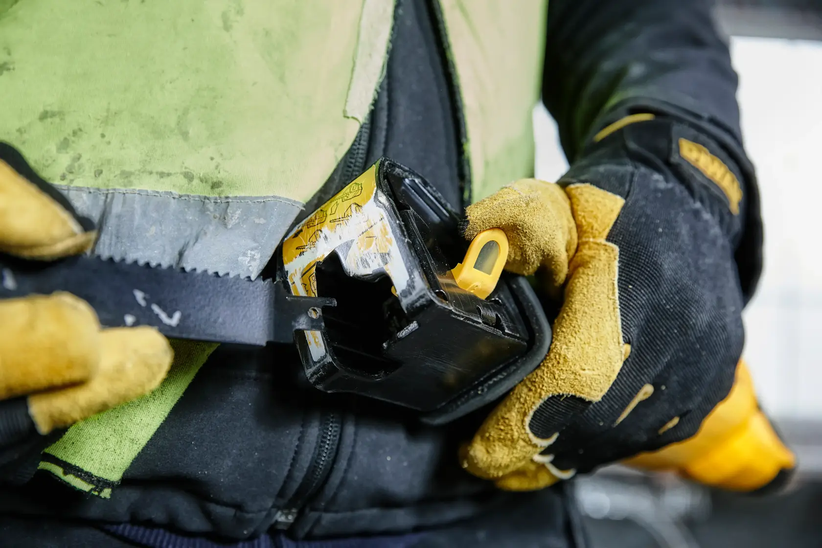 Gloved hands attach a DEWALT tool to a belt, showing close-up of work gear and rugged gloves.