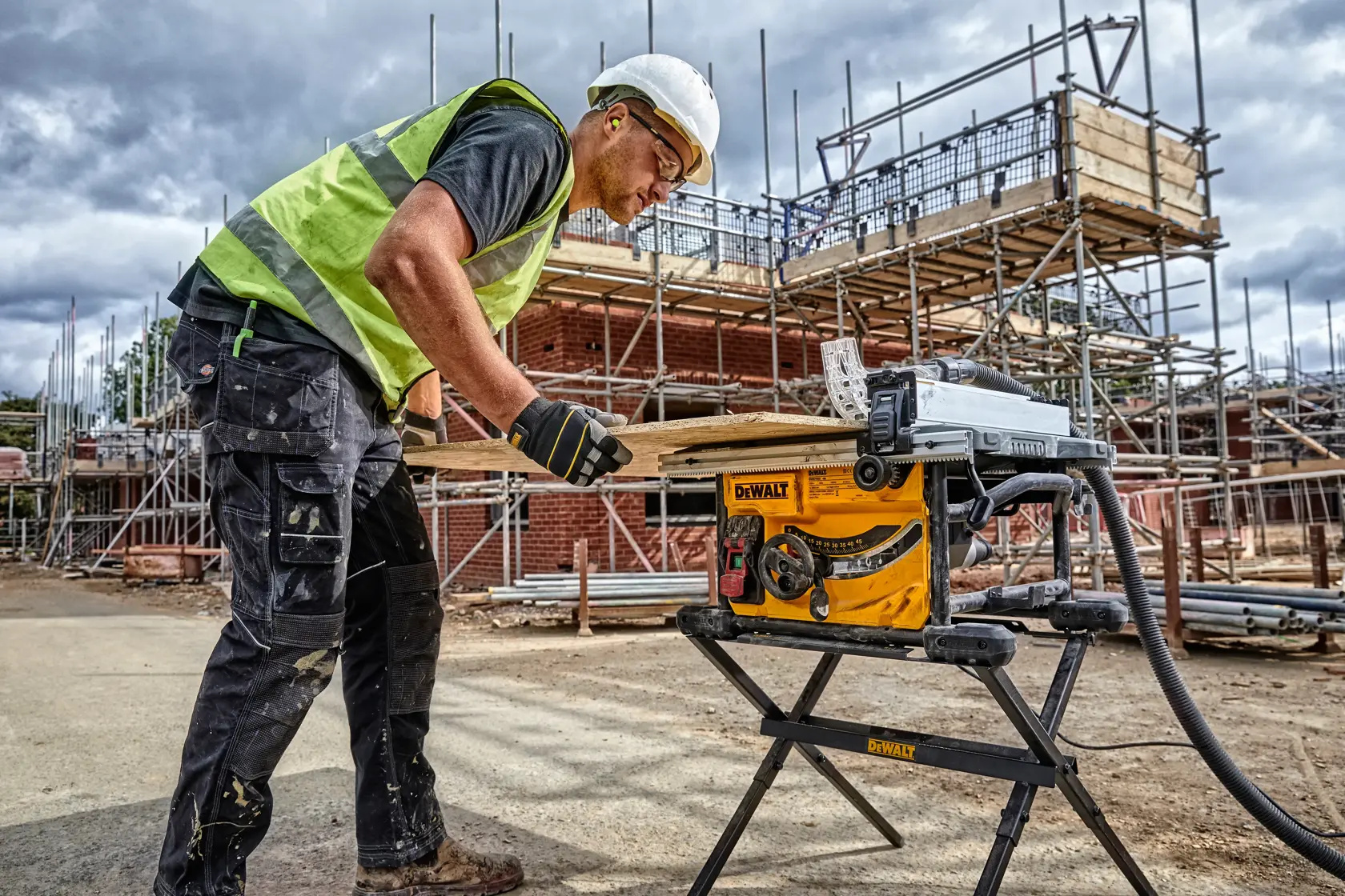 DEWALT DWE7485WS and DWE7485 saw used outdoors at construction site. Worker cuts wood. Scaffolding in background.