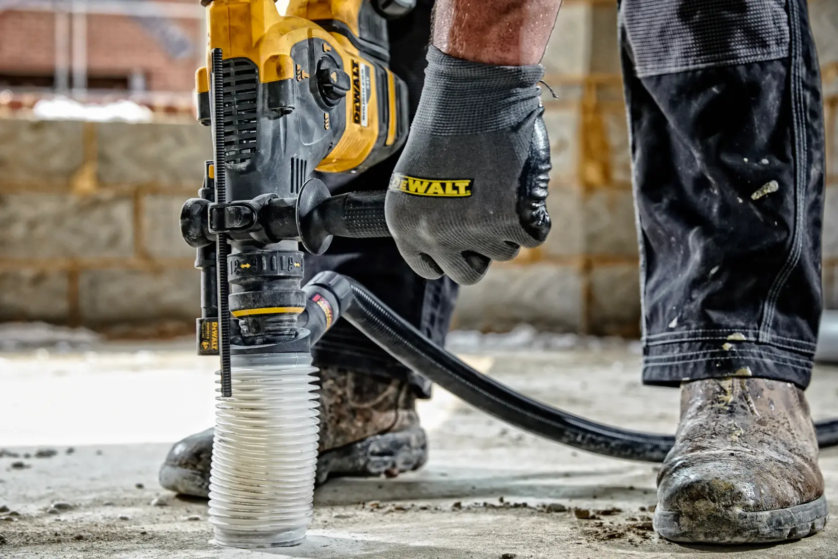 DEWALT dust extractor attached to a power tool in use on a concrete floor at a construction site.