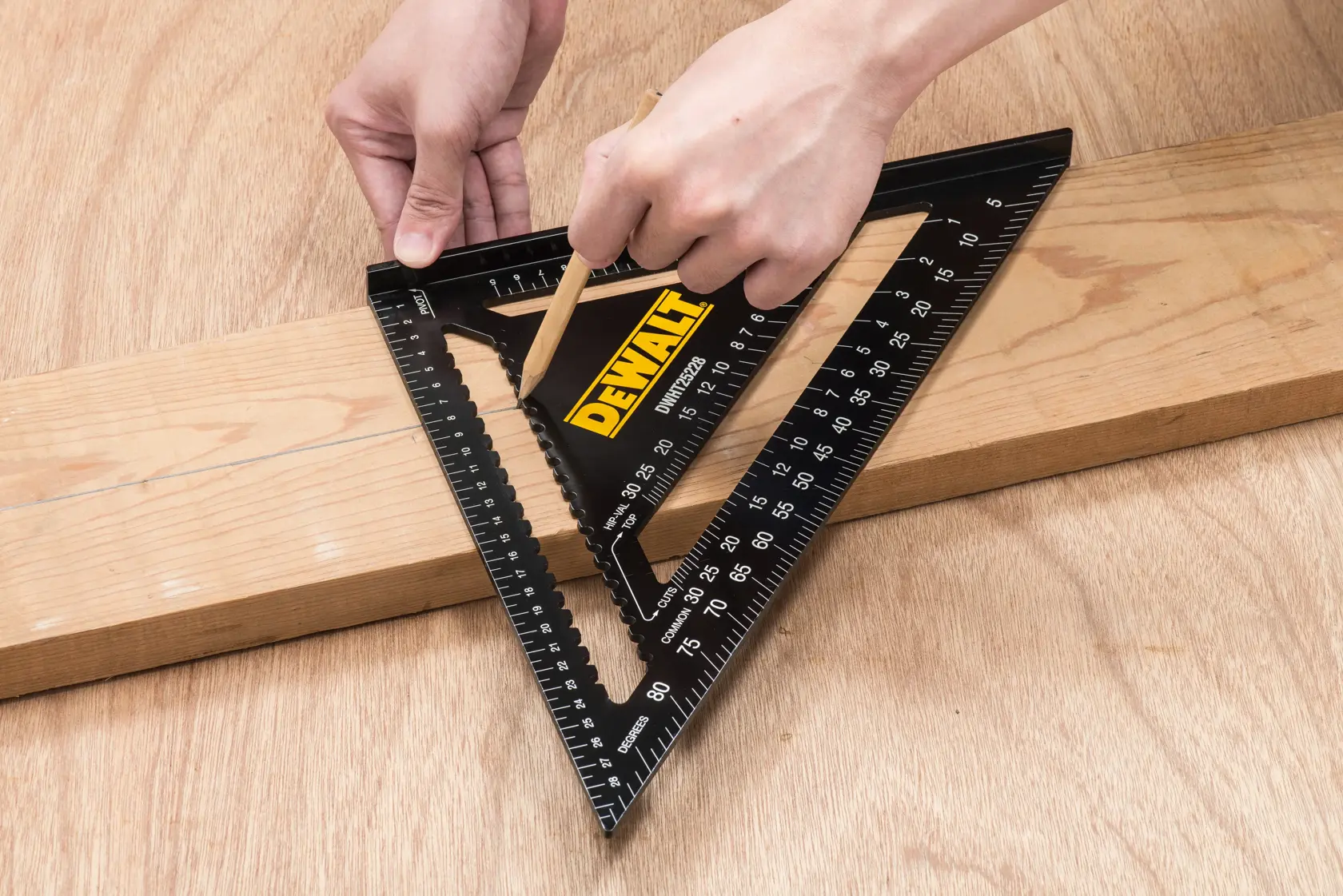Person using a DEWALT DWHT25228-0 black triangular rafter square to mark a straight line on a wooden plank with a pencil.