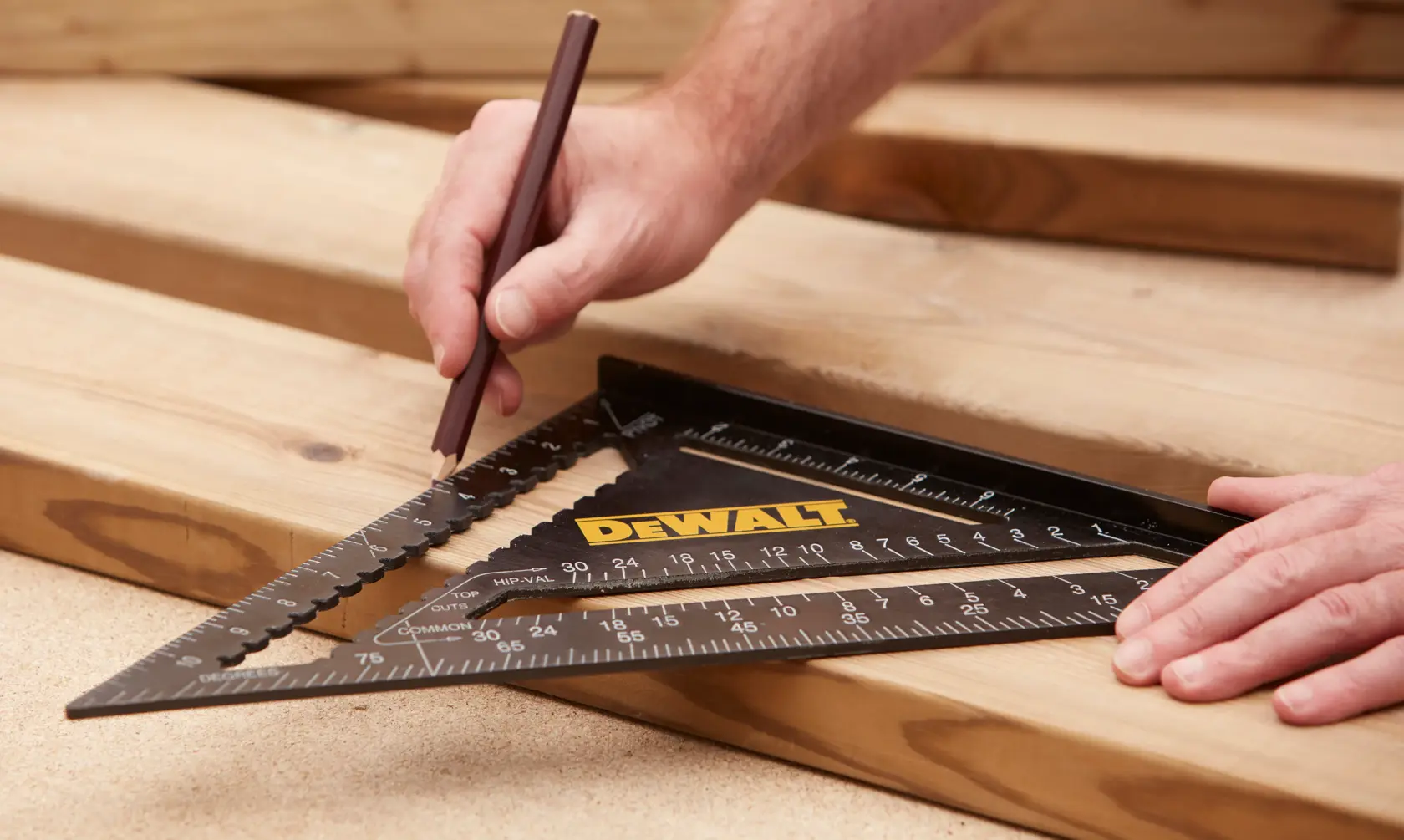 Person marking wood with a pencil using a DEWALT triangular square tool for precise measurements.
