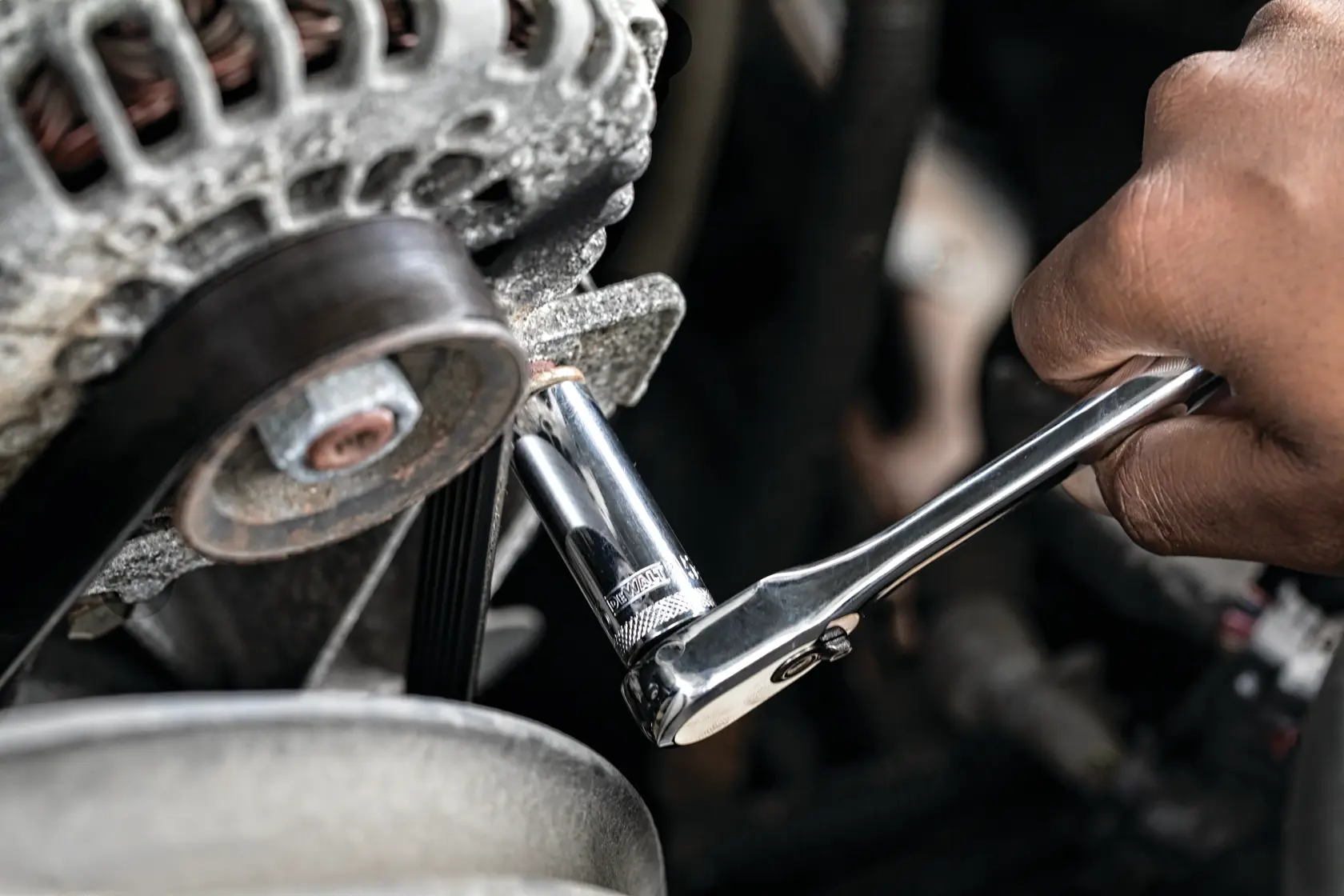 Hand using a DEWALT ratchet wrench to tighten a bolt on an engine part.