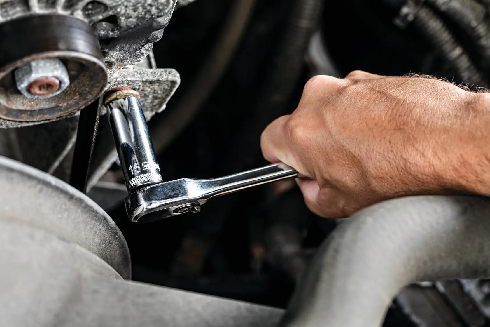 Hand using a DEWALT ratchet wrench to loosen or tighten a bolt on a mechanical part.