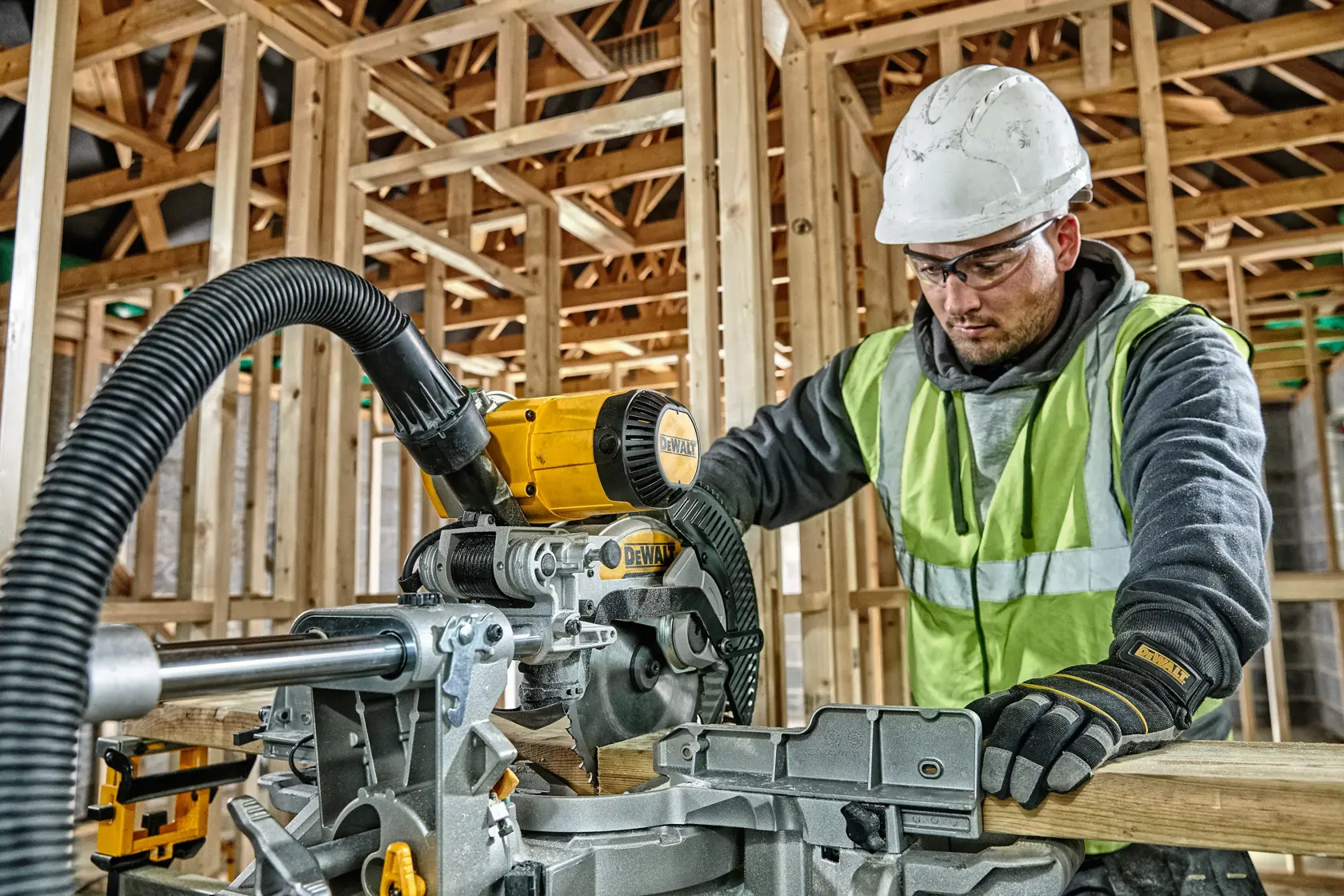 Worker using a DEWALT DWS727 saw at a construction site, wearing safety gear and gloves.