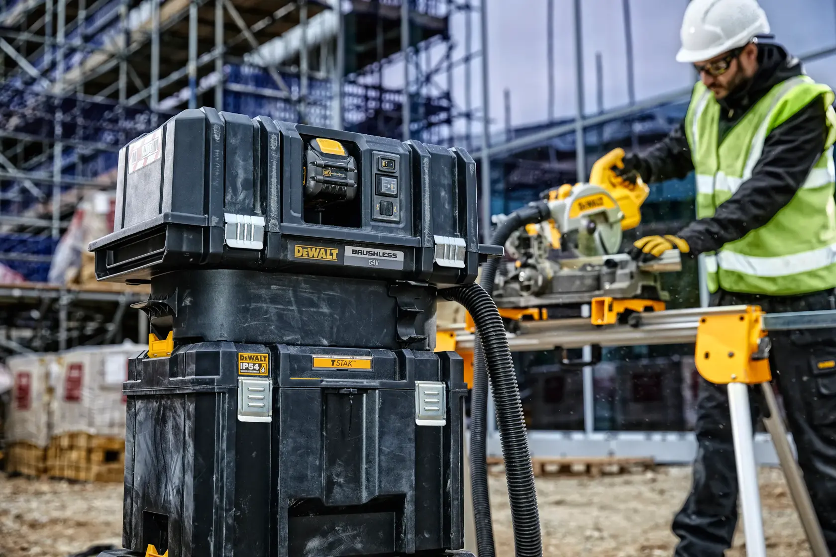 DEWALT tool storage and vacuum system on a construction site, worker using power tool in background.